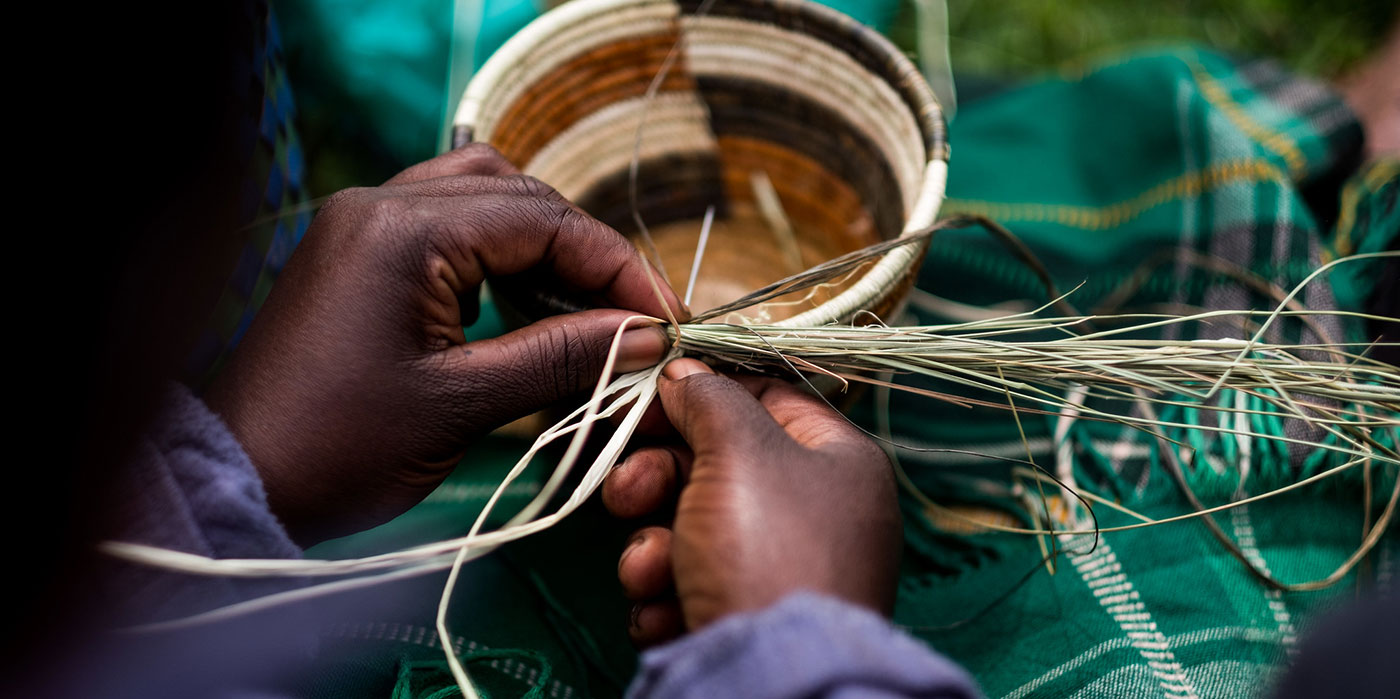 September 2017. Women with a local artisans group are learning to weave traditional baskets as handicrafts for sale to tourists. The organization promotes close collaboration among the members, and they often help each other with small loans and technical skills. Unfortunately, they were evicted from their previous workshop and showroom and are now looking for another location. Nkuringo, Uganda. Photograph by Jason Houston for USAID