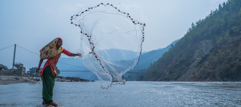 A fisher woman in Nepal uses traditional methods to fish in the Karnali River. Credit Sudin Bajracharya for USAID