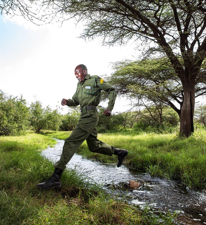 A ranger jumps over a stream flowing from Chaffa Springs in Nakuprat Gotu Community Conservancy