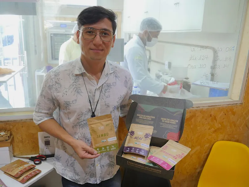 A man in glasses holds small brown bags of food. 