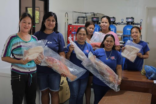 Several women smiling at a fish processing facility. 